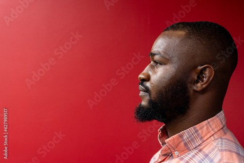 Side profile view of african american businessman against red background, copy space photo