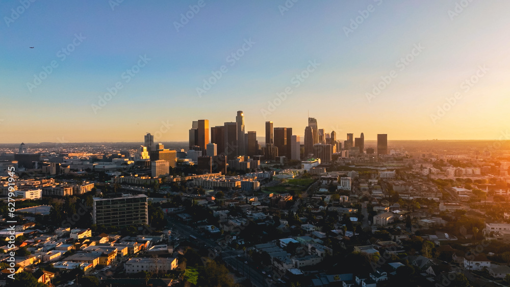 Fototapeta premium City skyline of Los Angeles at sunset with buildings reflecting the warm colors of the sky