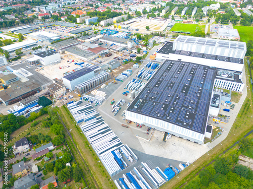 Aerial view of modern storage warehouse with solar panels on the roof. Logistics center in industrial city zone from drone view. Background texture concept.