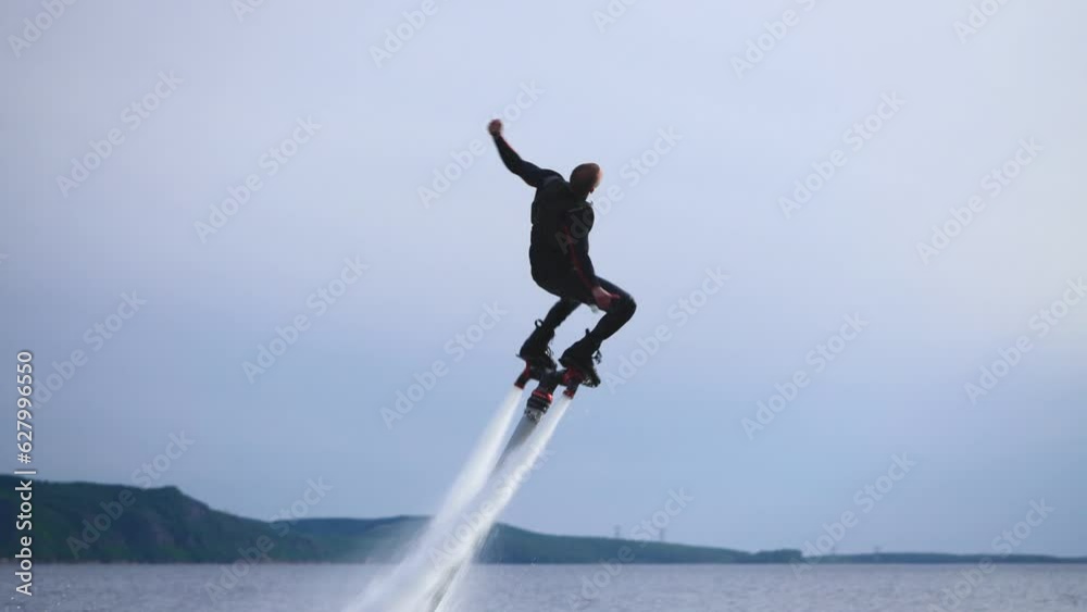 Flyboard, a new extreme sport. A man, a flyboarder, performs flips over the water. An agile and trained athlete. Water activity. Flyboard, a new extreme sport. A man, a flyboarder, performs flips over the water. An agile and trained athlete. Water activity.