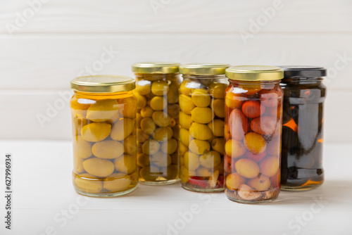 Delicious green, black and red olives. Pickled olives in glass jar. On a wooden background.Tasty olives. Close-up. Vegan.Place for text. copy space.Assorted. Different types of olives.