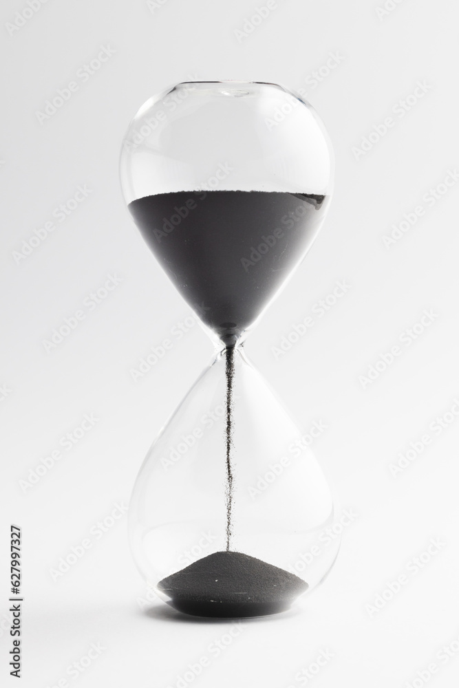 Close up of hourglass with black sand and copy space on white background Close up of hourglass with black sand and copy space on white background