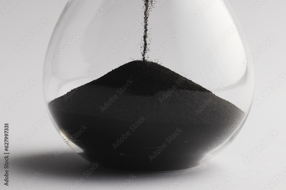 Fototapeta premium Close up of hourglass with black sand and copy space on white background