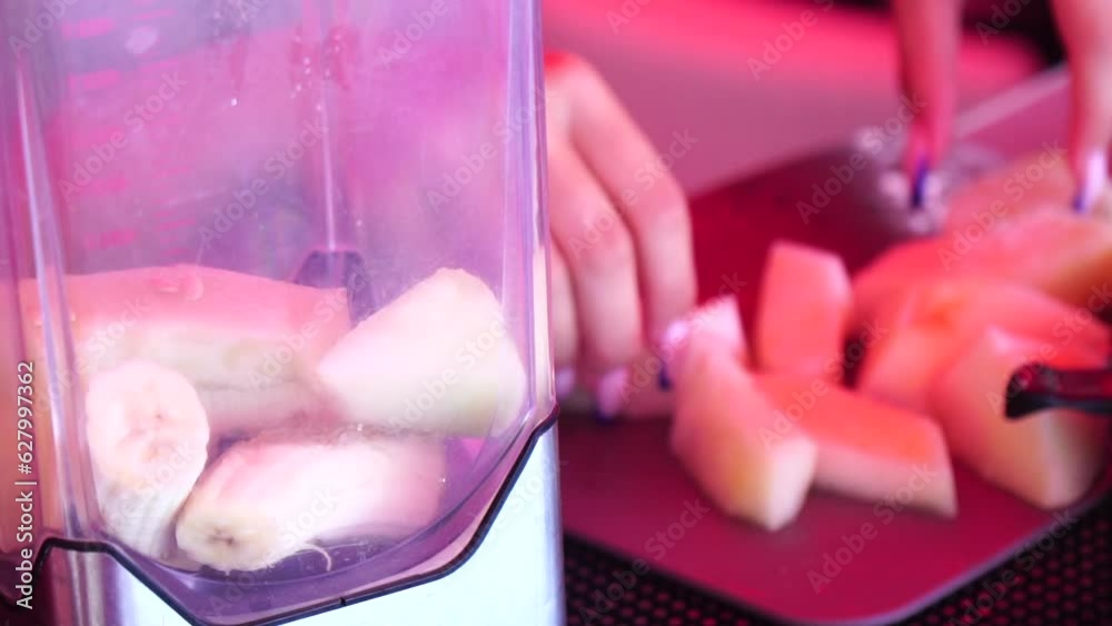 Woman making a fruit cocktail in a blender, smoothies preparation with melon and banana. woman puts cubs of ice and pieces of melon into a blender. Healthy summer drink concept. Woman making a fruit cocktail in a blender, smoothies preparation with melon and banana. woman puts cubs of ice and pieces of melon into a blender. Healthy summer drink concept.