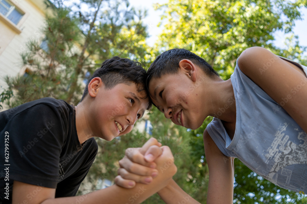 best friends in Uzbekistan enjoying there summer vacation in an outdoor park  playing games and the different expressions on their faces while playing in hot street make a friendship day special 
