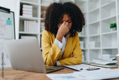 Burnout American African business woman in stress works with many paperwork document, migraine attack, Freelance, work at office