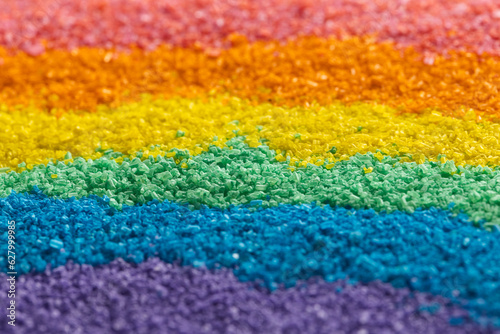 Close up of stripes of rainbow coloured sand and copy space background