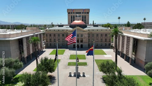 American flag and Arizona State flag waving in Phoenix, AZ at capitol building. Cinematic aerial establishing shot of government building. photo