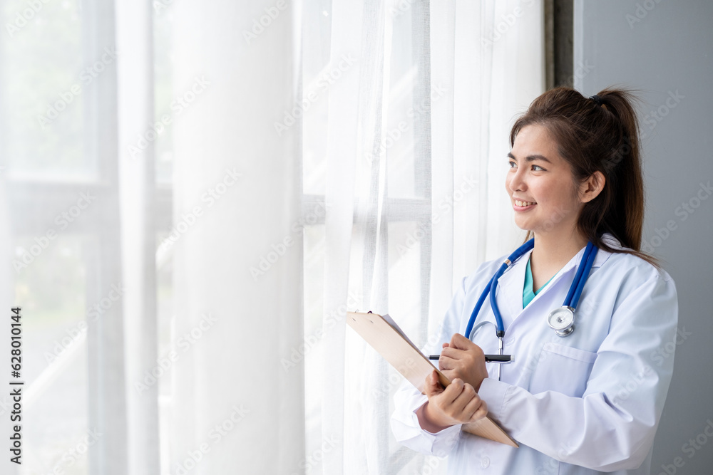 Young Asian female doctor standing on background and holding tappet document , Professional attractive young Asian female doctor in white uniform standing and spread hand with space Young Asian female doctor standing on background and holding tappet document , Professional attractive young Asian female doctor in white uniform standing and spread hand with space