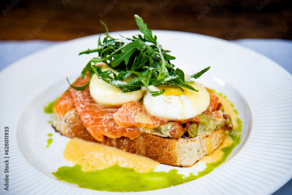 healthy breakfast with bruschetta with  salmon , poached eggs and arugula on white plate