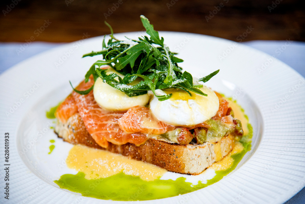 healthy breakfast with bruschetta with salmon , poached eggs and arugula on white plate healthy breakfast with bruschetta with salmon , poached eggs and arugula on white plate