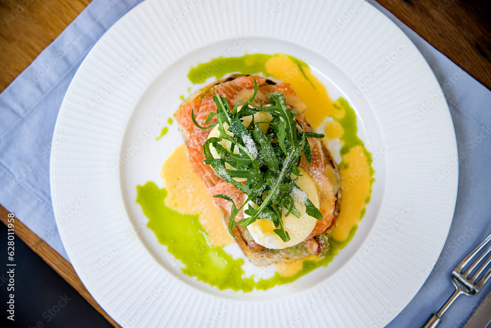 healthy breakfast with bruschetta with salmon , poached eggs and arugula on white plate healthy breakfast with bruschetta with salmon , poached eggs and arugula on white plate