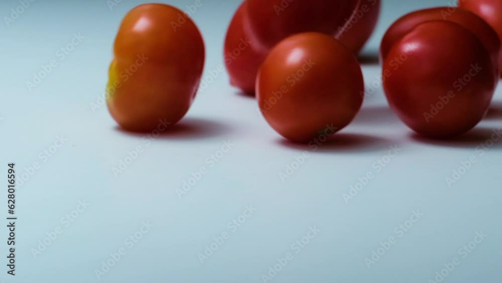 cherry tomatoes fall on a white surface in studio view. Slow motion cherry tomatoes fall on a white surface in studio view. Slow motion