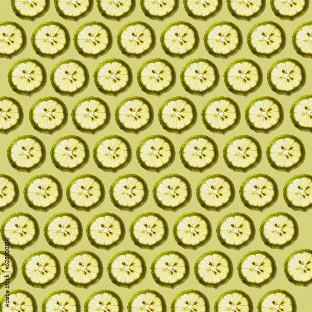 Fresh lemon slices against pale green with shadow forming a beautiful wallpaper texture pattern background. Fresh lemon slices against pale green with shadow forming a beautiful wallpaper texture pattern background.