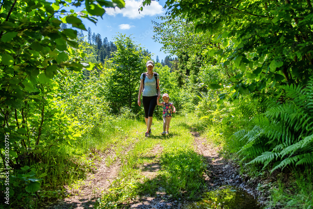 Obraz premium Mother with baby girl walking through green forest