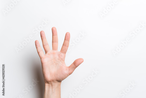 A close-up of a man's hand shows gesture number five or greeting on a white background.