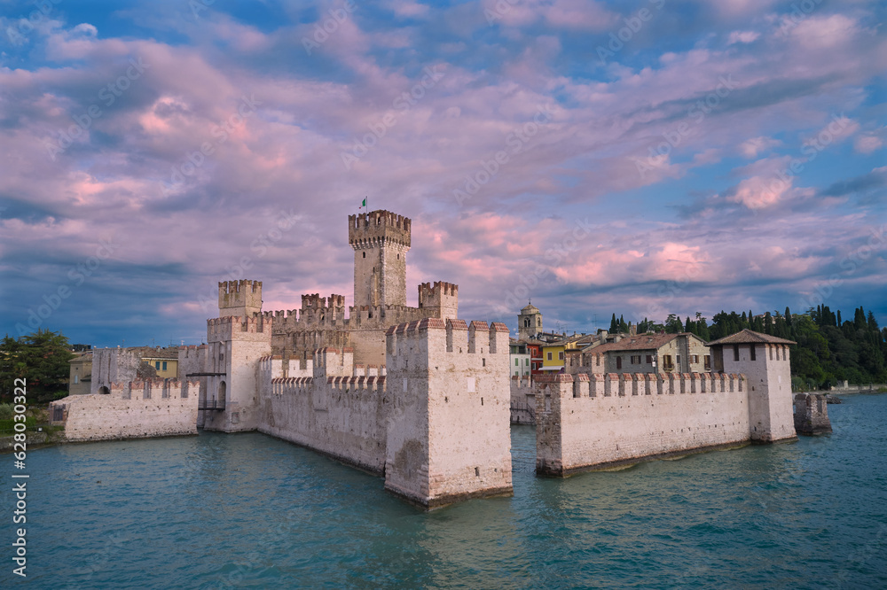 Pink clouds over Scaliger Castle. Scaliger Castle Sirmione on Lake Garda in Italy. Morning view of Scaliger Castle Sirmione. Sirmione at sunrise.