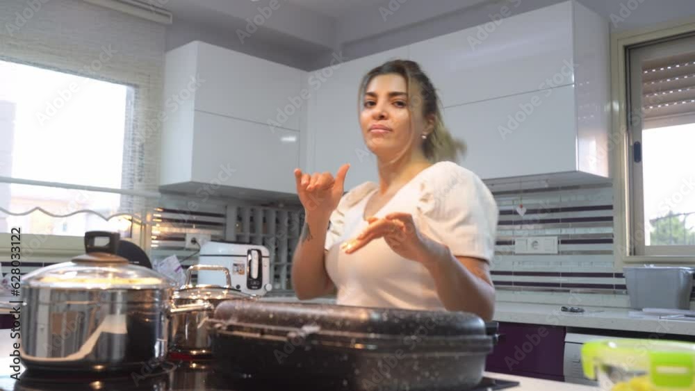 Middle Eastern cute happy woman dancing and singing while cooking dinner in kitchen at home. Frying burger, at pan domestic candid lifestyle routine. Middle Eastern cute happy woman dancing and singing while cooking dinner in kitchen at home. Frying burger, at pan domestic candid lifestyle routine.