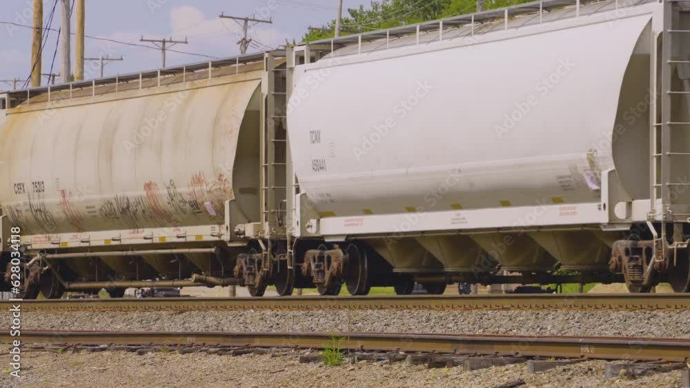 a train pulling white hopper cars rolling along the railroad tracks in the rust belt of Youngstown, Ohio a train pulling white hopper cars rolling along the railroad tracks in the rust belt of Youngstown, Ohio