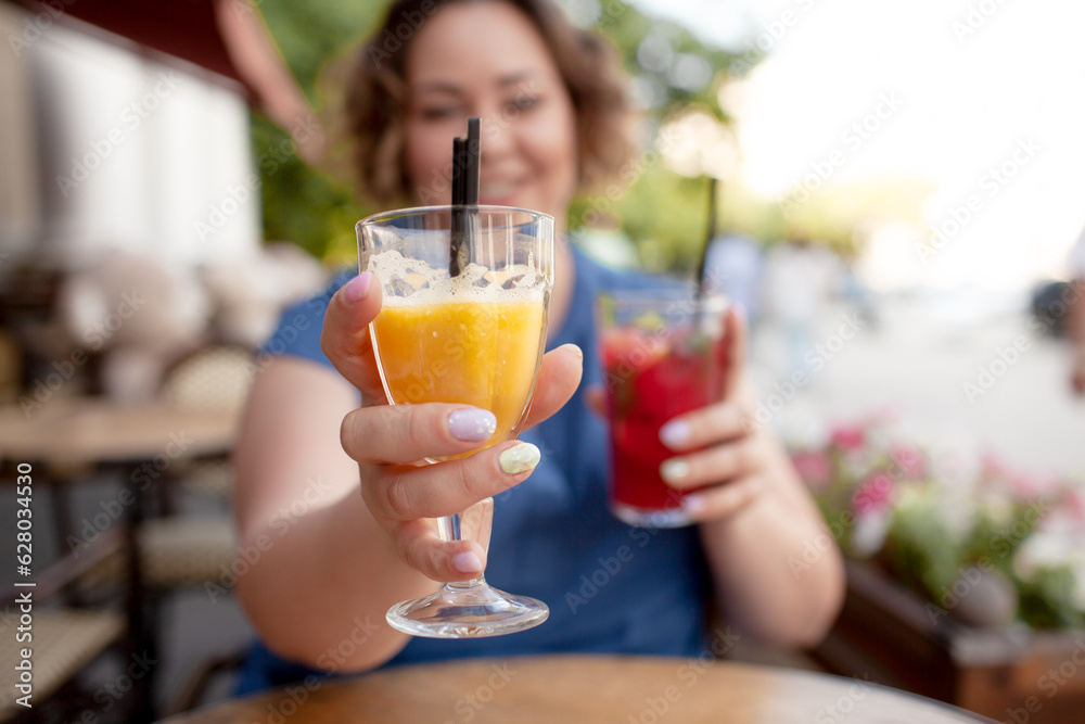 Beautiful young woman sit in cafe with glass of cooly drink. Plus size woman  drink red juice and smiling