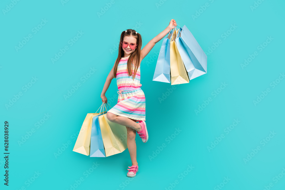 Full length photo of adorable cheerful girl dressed trendy striped clothes rejoice boutique purchases isolated on blue color background