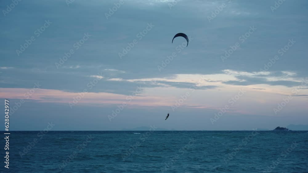 A beautiful kitesurfer jumps and rides a sail in the evening twilight at sunset. Slow motion A beautiful kitesurfer jumps and rides a sail in the evening twilight at sunset. Slow motion