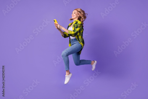 Full body photo of funny blogging jump woman run with samsung iphone record video instagram broadcast isolated on violet color background