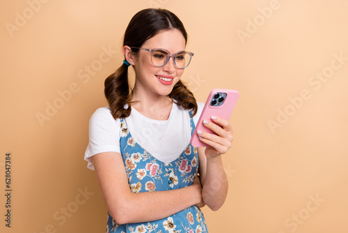 Photo of cute sweet girl dressed flower print overall communicating instagram twitter telegram facebook isolated beige color background