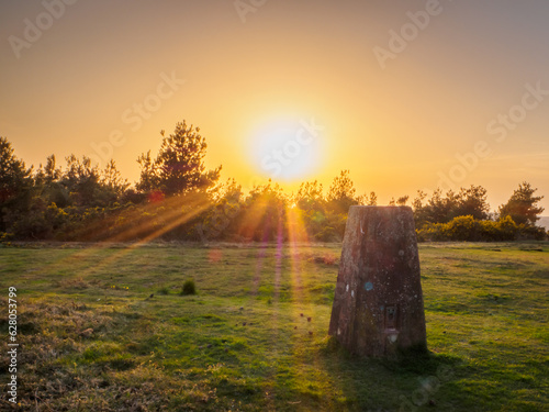 The sun setting behind a trig point