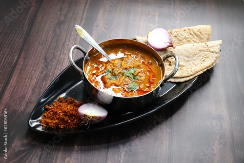 Traditional Sev bhaji or sev tamatar nu Shaak with Jowar Bhakri. Sev is a crisp fried gram flour vermicelli. Served with chopped onion and lemon. with Copy space. Its a sweet and spicy indian curry. photo