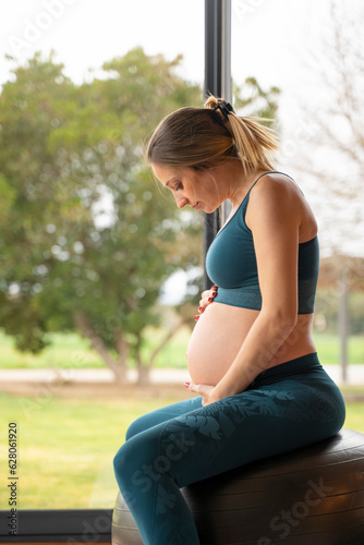 Blonde pregnant woman practicing yoga with a big ball at home