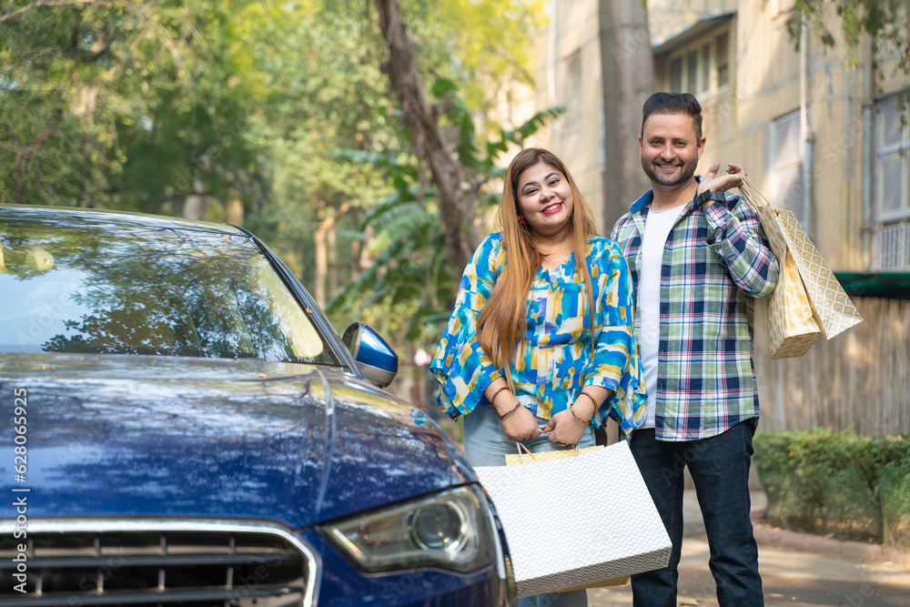Indian couple standing with his car after shopping and giving happy expression.