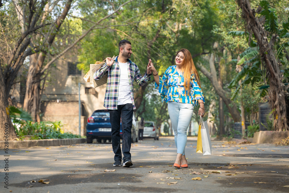 Cheerful indian couple walking along the street after shopping