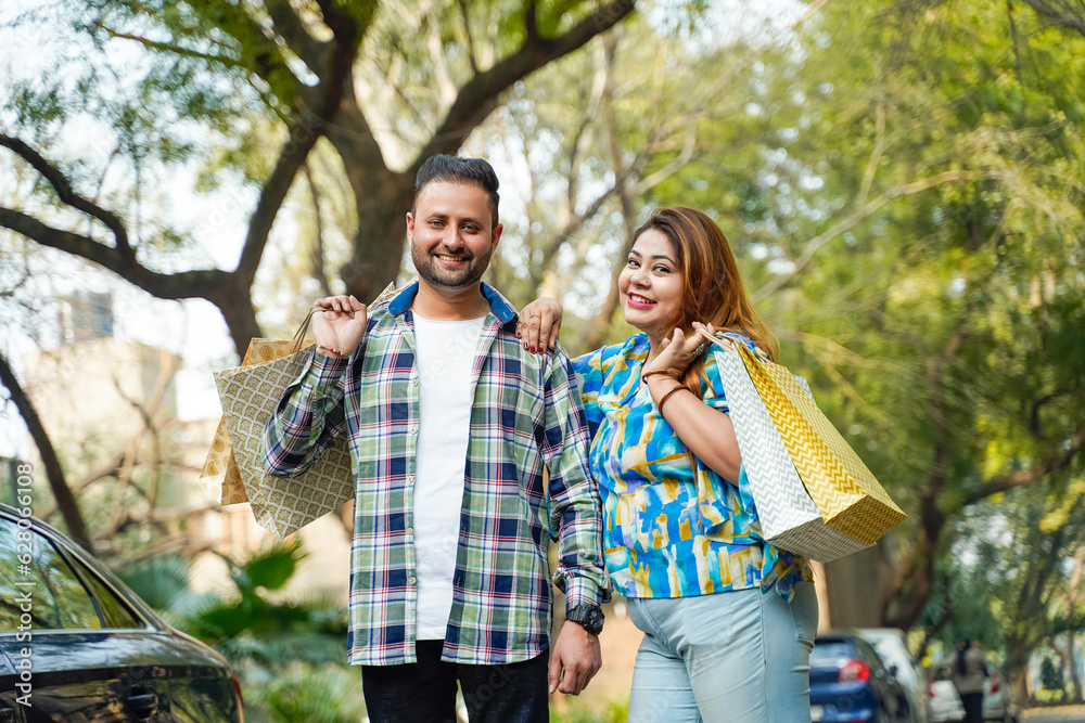 Cheerful indian couple walking along the street after shopping