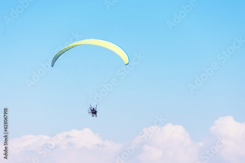 Paragliding, people take off from the beach on the ocean coast during sunny day.