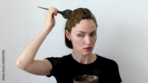 Beautiful woman dyes her hair with an herbal mixture of henna and basma to produce a brown color