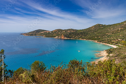 Rocky coastline and a deserted sandy beach meeting the turquoise Mediterranean sea at Galéria on the west coast of Corsica, France