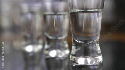 Tableau sur toile Pouring Vodka into Shot-Glasses Slow Motion