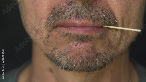 Сlose-up of an unshaven man's chin with a toothpick in his mouth. A middle-aged man nervously chews a toothpick. 4K