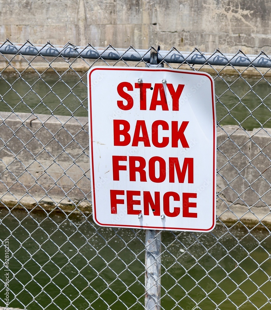 A close view of the red and white sign on the fence. A close view of the red and white sign on the fence.