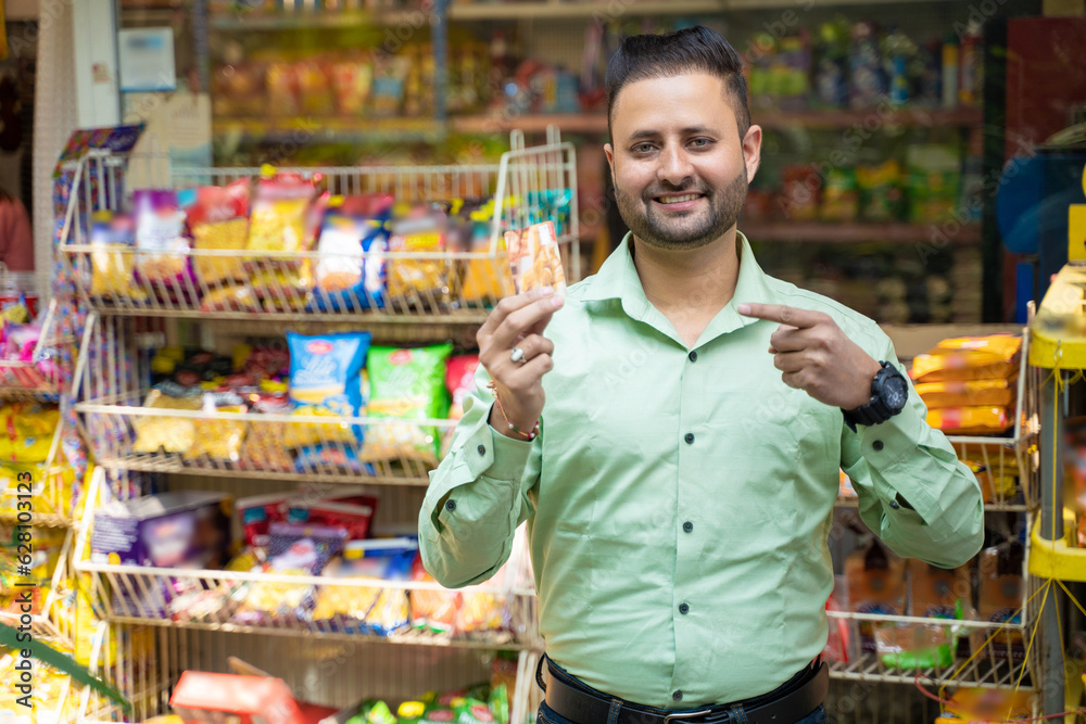 Indian man showing bank card at grocery shop.