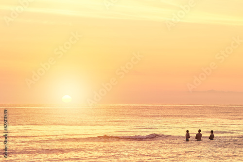 Silhouettes of a young group of people swimming in the ocean at sunset
