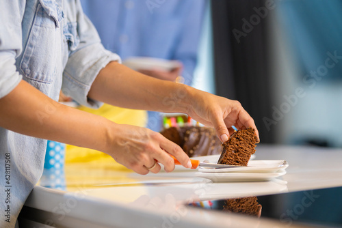 Young girl cuts the slice of cake and puts  on the plate