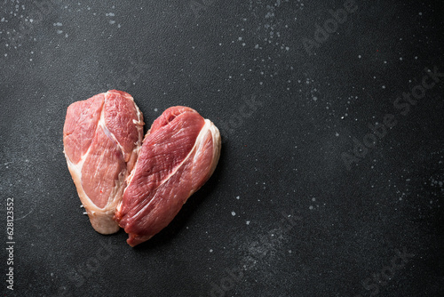 Raw meat steaks at black background. Fresh meat. Top view with space for text.