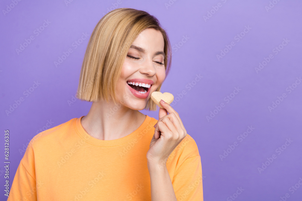 Photo of young lovely girl bite gingerbread cookie heart figure hungry pastry enjoy dessert sweet food isolated on purple color background Photo of young lovely girl bite gingerbread cookie heart figure hungry pastry enjoy dessert sweet food isolated on purple color background