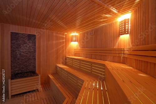 Seat in sauna room. Empty wooden steam room with stone heater.Sauna room for good health. Sauna room with traditional sauna accessories.Healthy and spa life style.