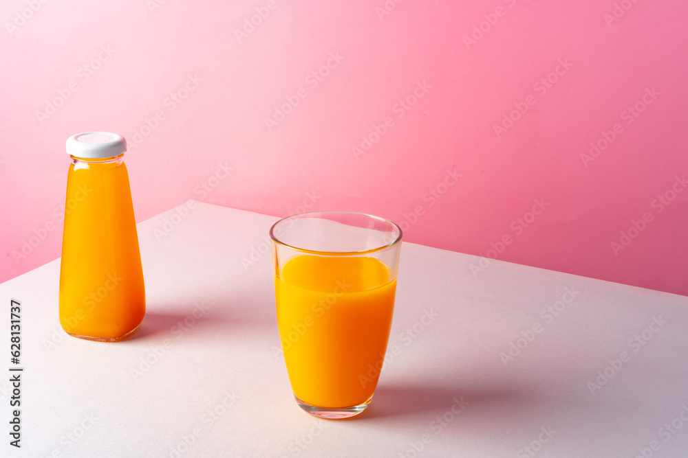 Orange juice on white table against pink background Orange juice on white table against pink background