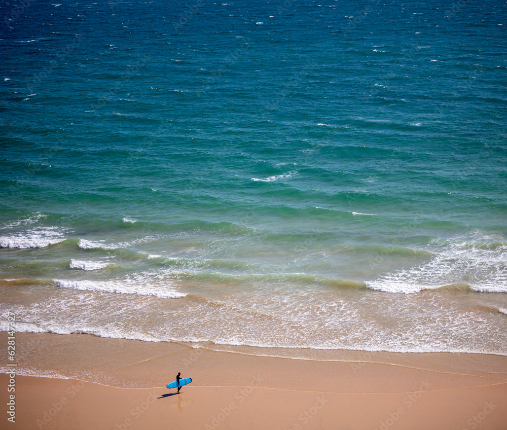Surfer gets ready to enter the sea Surfer gets ready to enter the sea