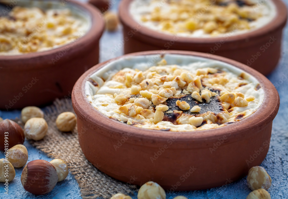 Baked rice pudding turkish milky dessert sutlac in earthenware casserole with hazelnuts Baked rice pudding turkish milky dessert sutlac in earthenware casserole with hazelnuts