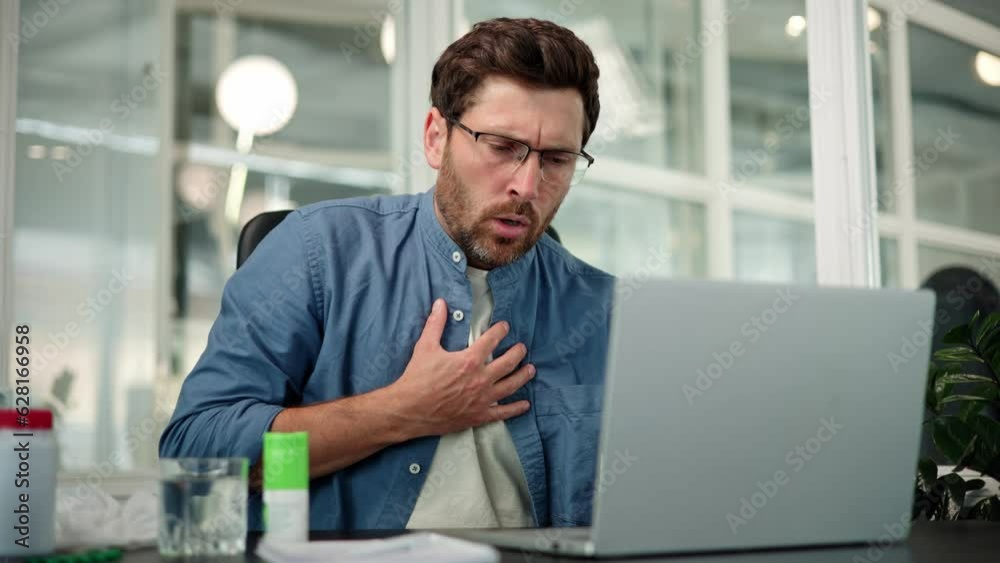 Chest pain, trouble breathing. Closeup of working bearded man in glasses, difficulty breathing or chest pain, touches his chest with hand. Heart attack, thoracic osteochondrosis, panic attack concept.